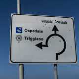 Un cartello stradale a fondo bianco forato da dodici colpi di arma da fuoco...